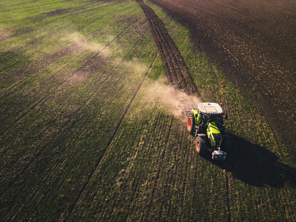 Modern tractor with rotary cultivator in field